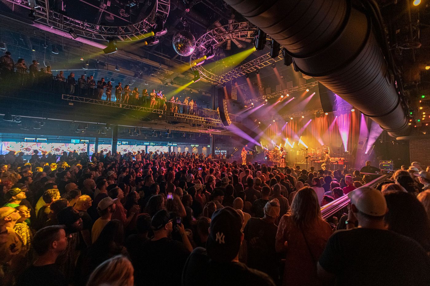 A packed concert at Brooklyn Bowl Las Vegas with the disco ball and stage lights overhead.