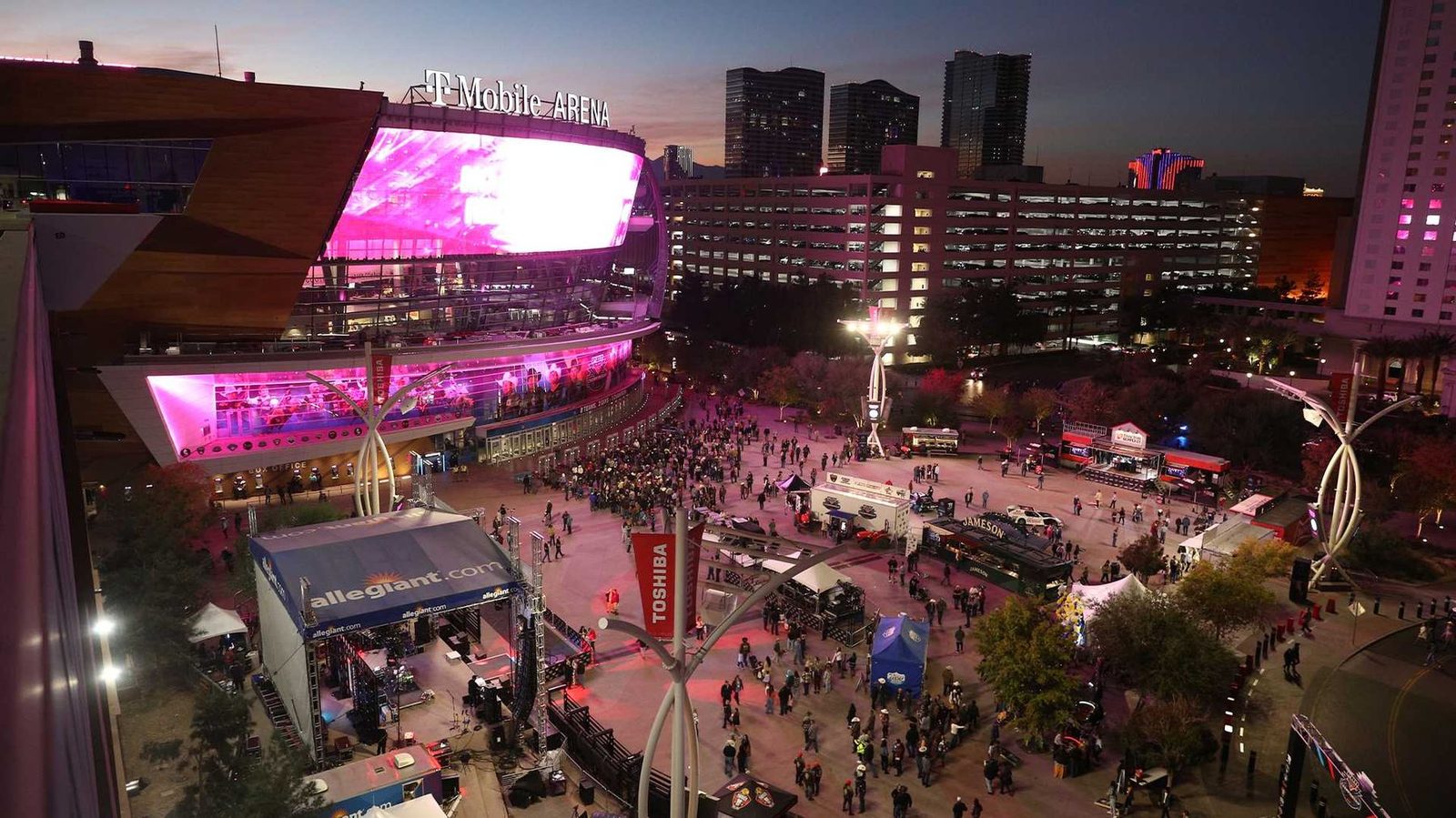 T-Mobile Arena at dusk during the PBR World Finals, with the Allegiant activation and crowds filling Toshiba Plaza.